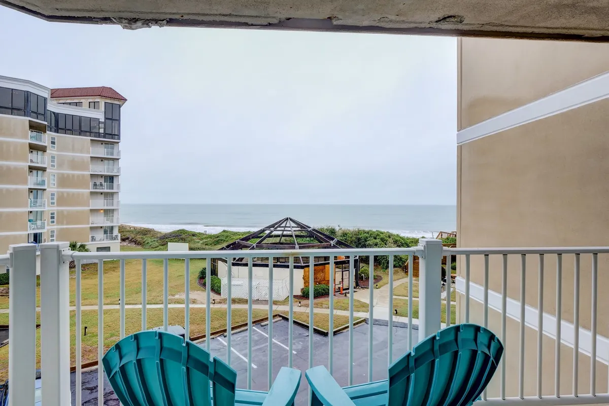 This image features a pair of adirondack chairs arranged to face an expansive ocean view, with a charming gazebo nearby. The scene is tranquil, inviting guests to relax and soak in the natural beauty, whether at sunrise or sunset. The seating setup encourages togetherness while showcasing the direct proximity to the water.