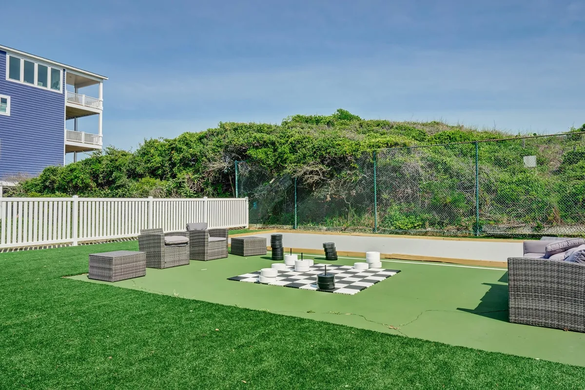 This image showcases a spacious outdoor area featuring a large chessboard, modern seating, and lush greenery. The setting invites guests to relax, socialize, or enjoy a playful match, all while basking in the fresh air and natural surroundings.